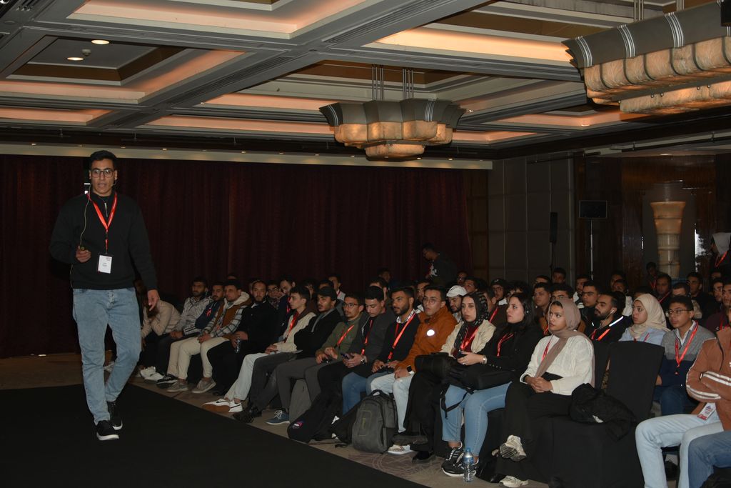 A speaker with a microphone walking in front of the audience