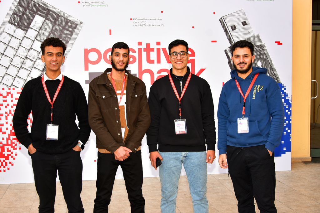 Four attendees in front of the Positive Hack Talks Cairo backdrop