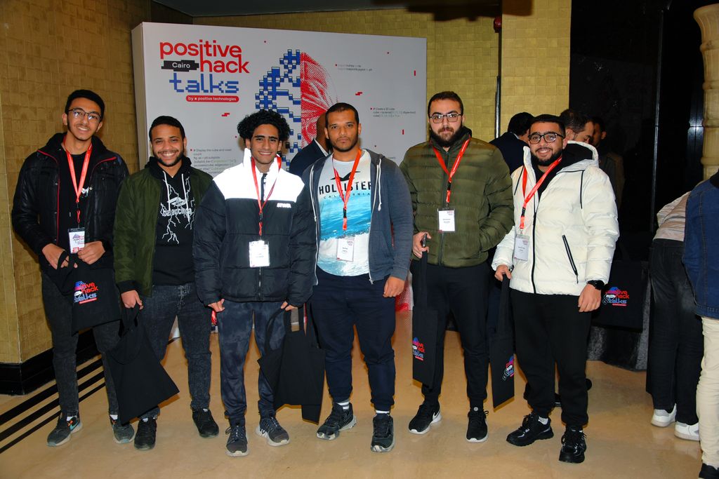 Attendees with Positive Hack Talks tote bags by the event banner