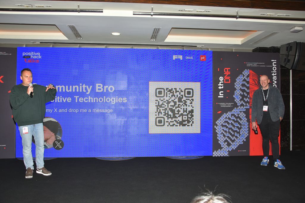 A speaker on stage in front of a slide with a QR code