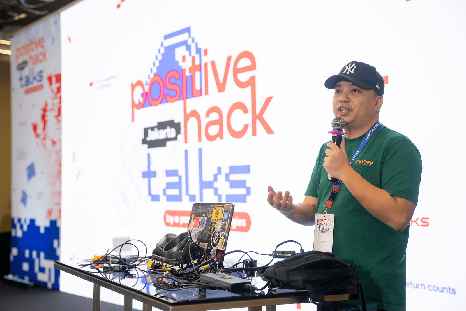 Positive Hack Talks Jakarta: a speaker on stage with hardware on the demo table