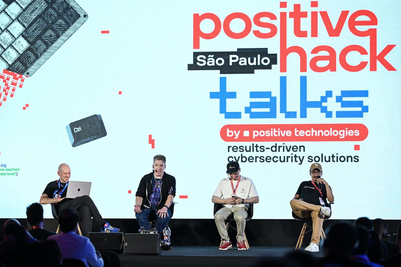 Four people seated on stage under the Positive Hack Talks São Paulo screen